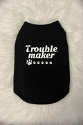 Black pet shirt with 'Trouble maker' text on a fluffy white surface