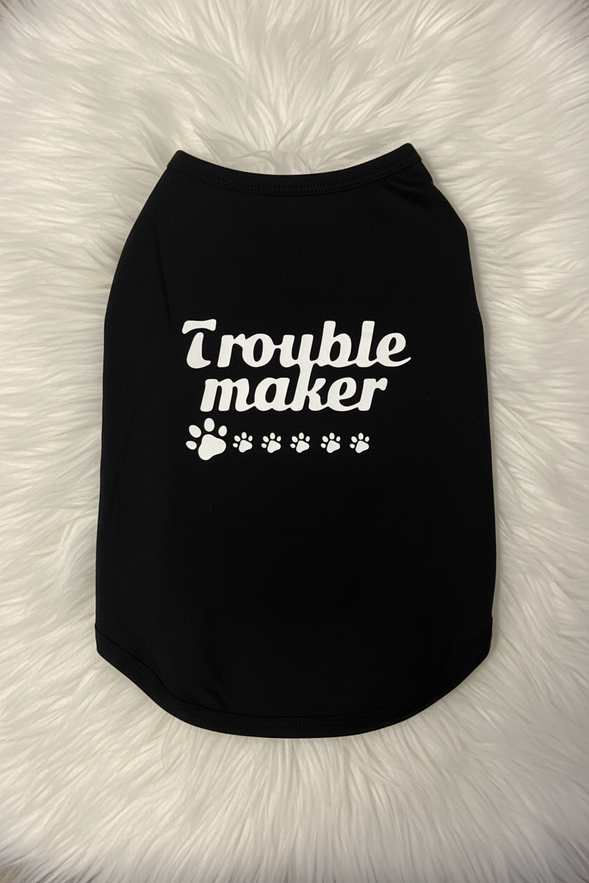 Black pet shirt with 'Trouble maker' text on a fluffy white surface