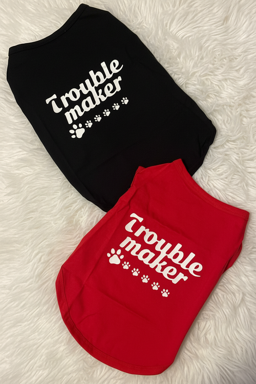 Black and red pet shirts with 'Trouble maker' text on a white fluffy surface