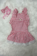 Pink checkered dress with ruffles and a matching bow on a white fluffy background