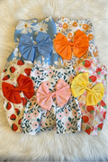 Set of colorful dog summer dresses with large bows on a fluffy white surface
