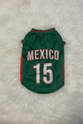 Green dog jersey with 'Mexico' and number '15' on a white fluffy surface