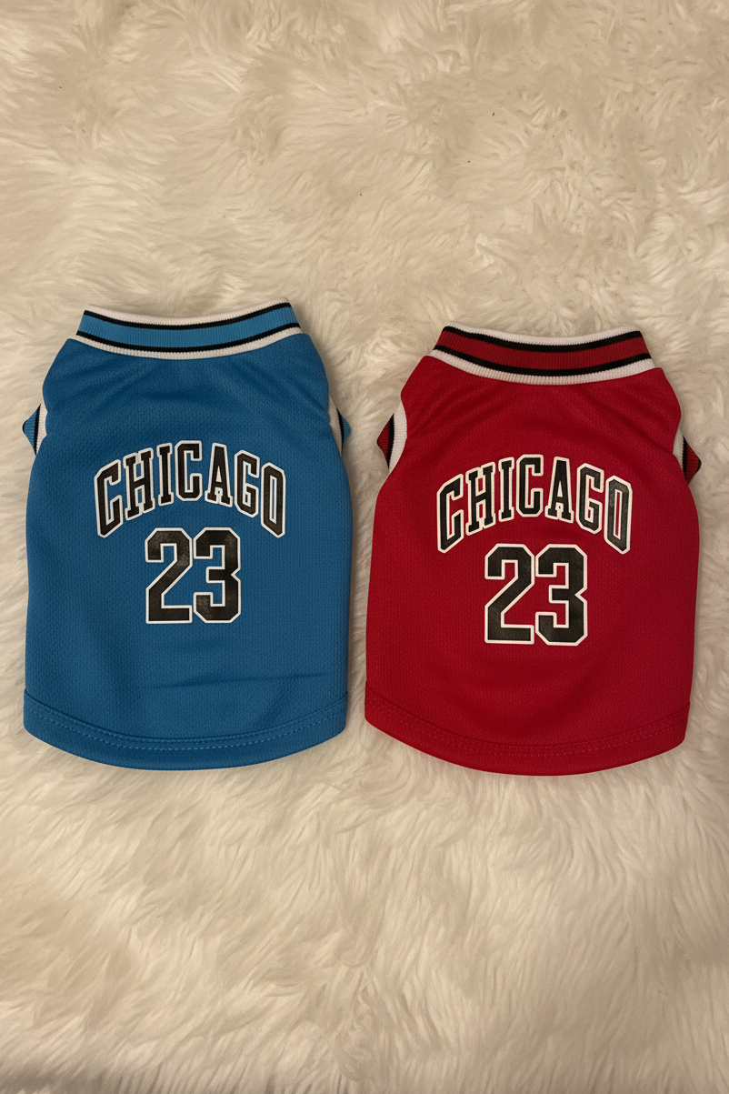 Two dog jerseys, one blue and one red, with 'Chicago 23' text on a fluffy white surface.