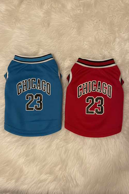Two dog jerseys, one blue and one red, with 'Chicago 23' text on a fluffy white surface.